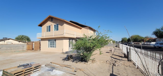 view of side of home featuring a fenced backyard, stucco siding, and a balcony