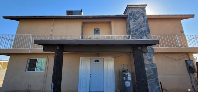 exterior space featuring stucco siding, a balcony, and water heater