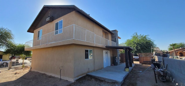 back of property featuring fence, a balcony, and stucco siding