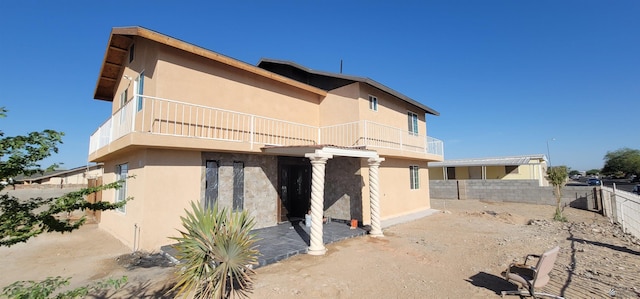 rear view of property with a fenced backyard, stucco siding, and a balcony