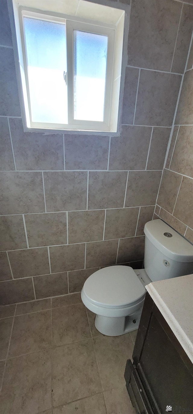 half bathroom featuring toilet, tile patterned floors, and vanity