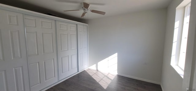 unfurnished bedroom featuring baseboards, dark wood-style floors, ceiling fan, and a closet