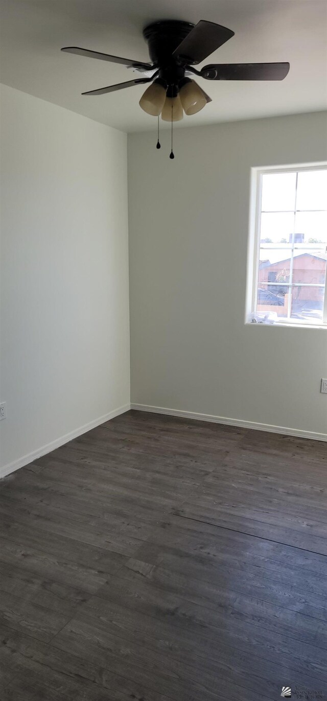spare room featuring baseboards, a ceiling fan, and dark wood-style floors