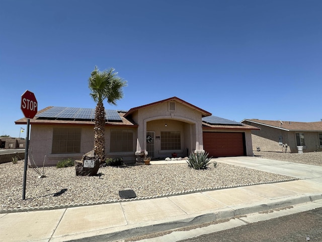 11228 E 25th St, Yuma, AZ 85367 - ranch-style home featuring stucco siding, roof mounted solar panels, a garage, and driveway