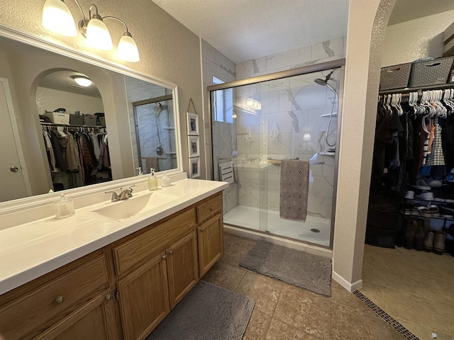 11228 E 25th St, Yuma, AZ 85367 - full bath with a textured wall, a shower stall, vanity, a walk in closet, and a textured ceiling