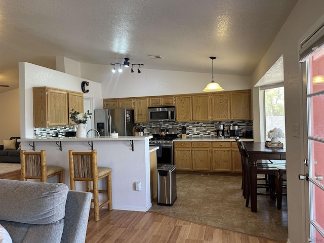 11228 E 25th St, Yuma, AZ 85367 - kitchen featuring stainless steel appliances, backsplash, vaulted ceiling, a peninsula, and a kitchen bar