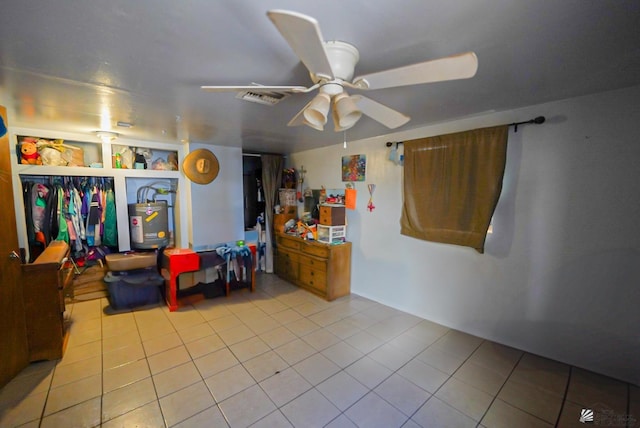 playroom featuring a ceiling fan, tile patterned flooring, water heater, and visible vents