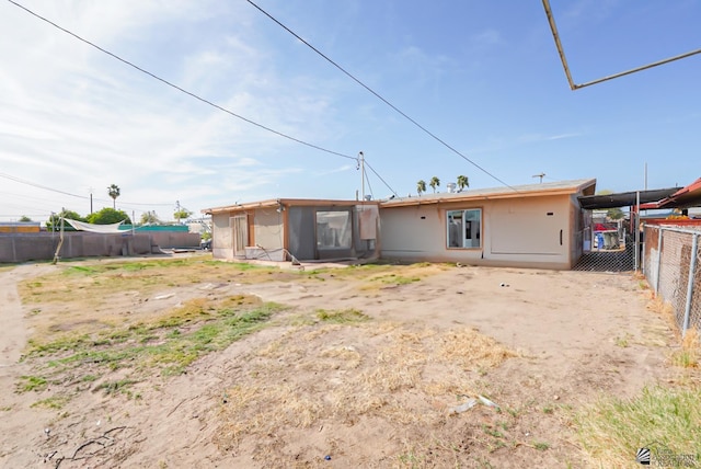 rear view of house featuring a fenced backyard and stucco siding