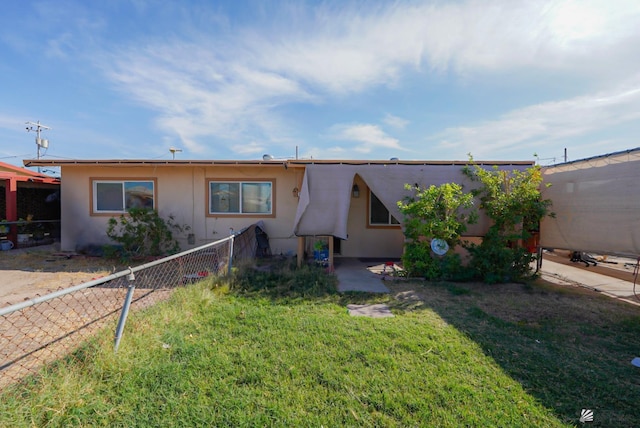 view of front of home with fence, stucco siding, and a front lawn