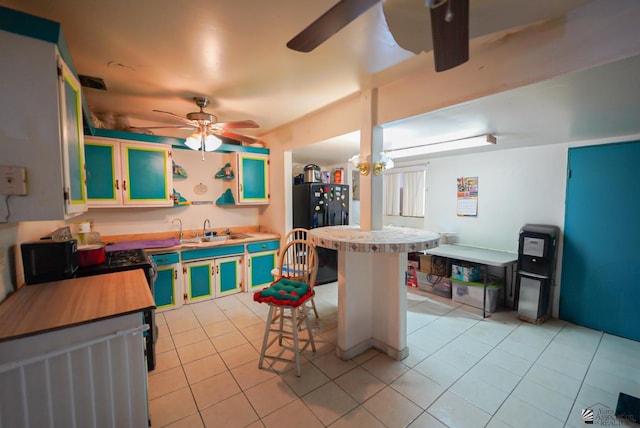 kitchen featuring a sink, freestanding refrigerator, a ceiling fan, and light tile patterned flooring