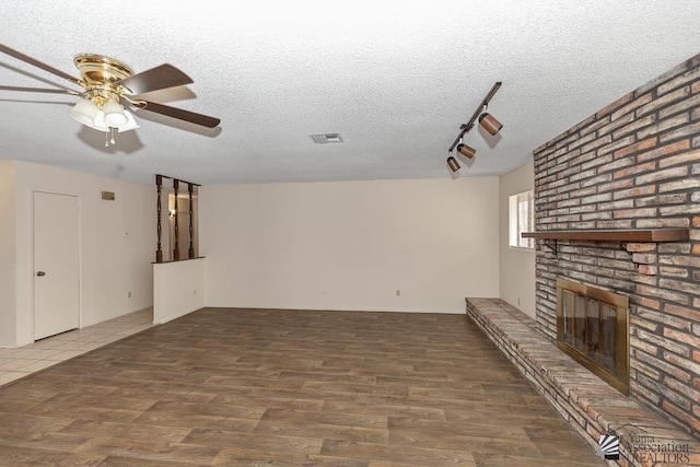 2413 W 13th Pl, Yuma, AZ 85364 - unfurnished living room with a ceiling fan, wood finished floors, a textured ceiling, a fireplace, and track lighting