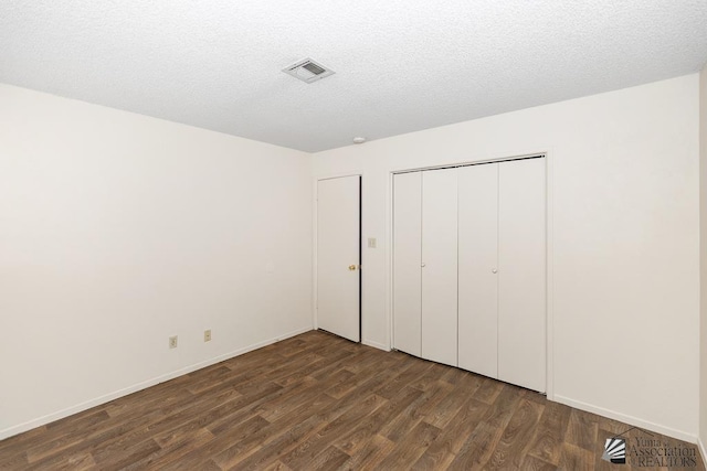 2413 W 13th Pl, Yuma, AZ 85364 - unfurnished bedroom with dark wood-style floors, a closet, a textured ceiling, and baseboards