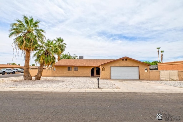 2413 W 13th Pl, Yuma, AZ 85364 - view of front facade with a garage, driveway, stucco siding, and fence