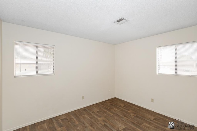 2413 W 13th Pl, Yuma, AZ 85364 - unfurnished room with dark wood-style floors, plenty of natural light, baseboards, and a textured ceiling