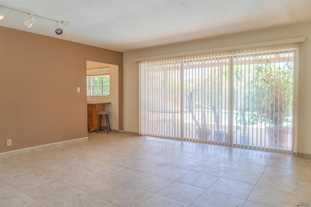 tiled empty room with baseboards and rail lighting