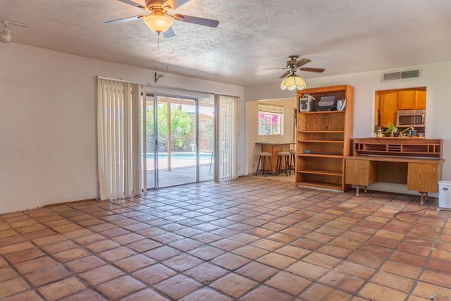 living area featuring a ceiling fan, a textured ceiling, and visible vents