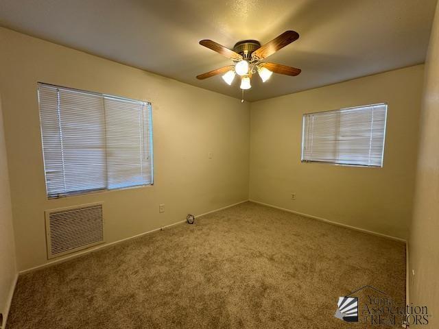 unfurnished room with ceiling fan, visible vents, baseboards, and carpet