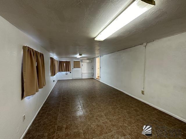 unfurnished room featuring a textured ceiling and baseboards