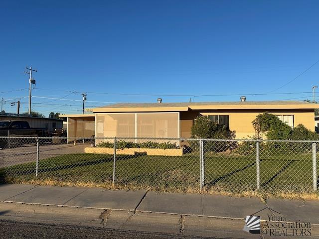 manufactured / mobile home with a carport, a fenced front yard, and a front lawn