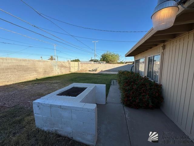 view of storm shelter featuring a lawn, a fenced backyard, and a patio area
