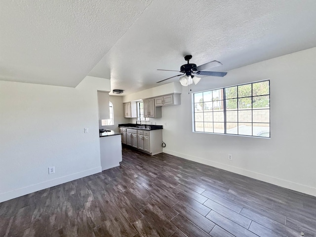 2472 S 18th Ave, Yuma, AZ 85364 - unfurnished living room featuring a textured ceiling, baseboards, dark wood-style floors, ceiling fan, and a sink