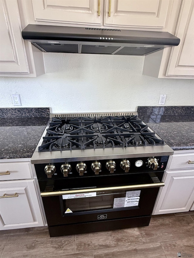 2472 S 18th Ave, Yuma, AZ 85364 - kitchen view of black gas range, under cabinet range hood, white cabinets, wood finished floors, and a textured wall