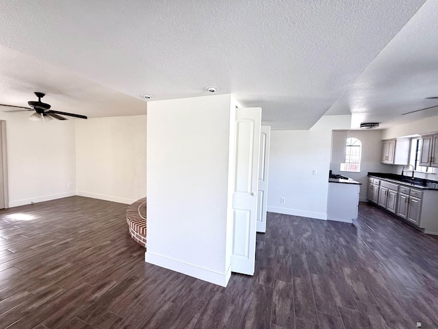 2472 S 18th Ave, Yuma, AZ 85364 - unfurnished living room featuring a textured ceiling, dark wood-style flooring, baseboards, a ceiling fan, and a sink