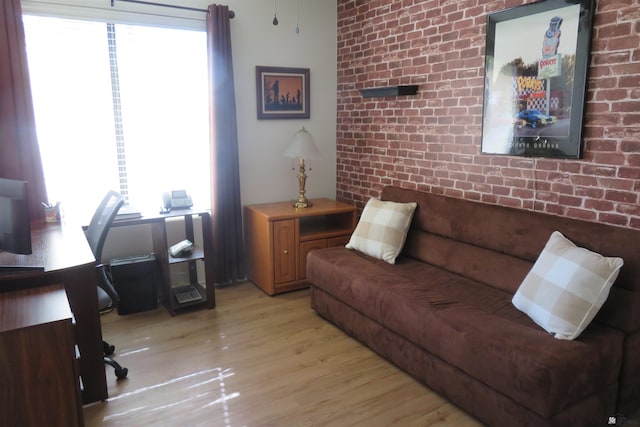 living room featuring plenty of natural light, light hardwood / wood-style floors, and brick wall