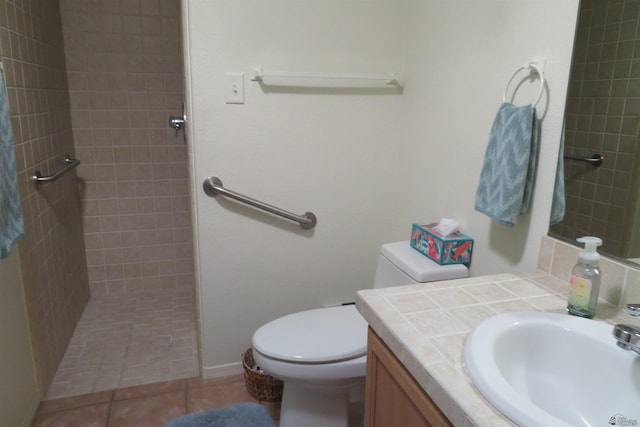 bathroom with tile patterned floors, toilet, vanity, and tiled shower