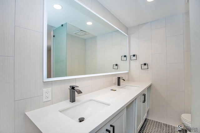 bathroom featuring vanity, tile walls, and toilet