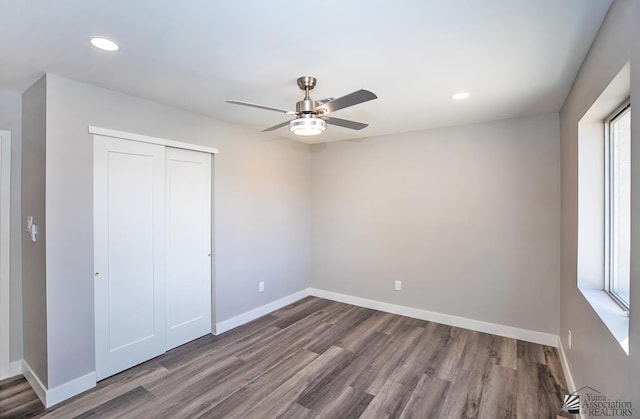 unfurnished bedroom with hardwood / wood-style flooring, ceiling fan, and a closet