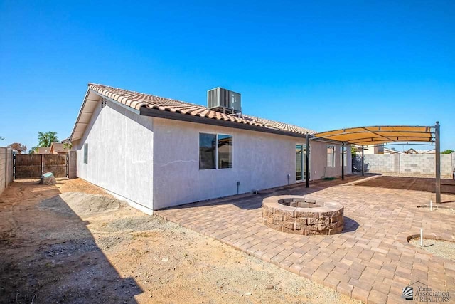 back of property with central AC, an outdoor fire pit, and a patio area