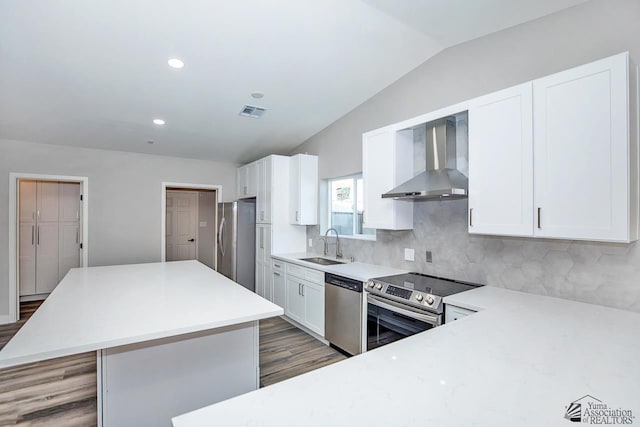 kitchen featuring a kitchen island, appliances with stainless steel finishes, sink, white cabinets, and wall chimney exhaust hood