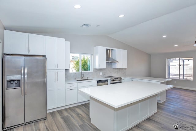 kitchen featuring white cabinetry, wall chimney range hood, sink, and appliances with stainless steel finishes