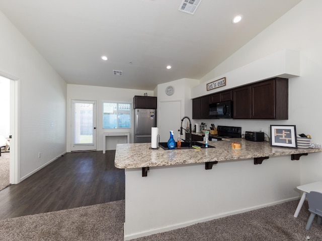 7335 E 36th Rd, Yuma, AZ 85365 - kitchen featuring black appliances, a peninsula, a kitchen breakfast bar, dark brown cabinets, and light stone countertops
