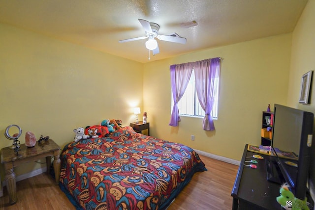 bedroom with a ceiling fan, baseboards, and wood finished floors