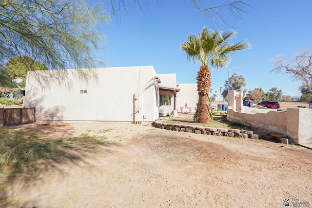 view of side of property featuring stucco siding and fence
