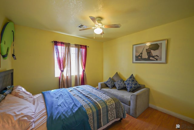 bedroom featuring a ceiling fan, baseboards, visible vents, and wood finished floors