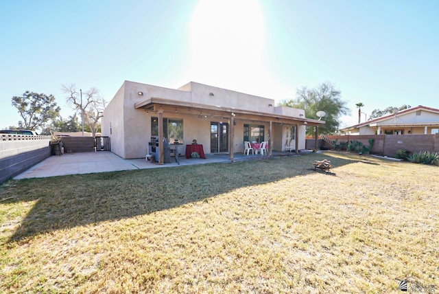 back of house featuring a yard, a fenced backyard, a patio area, and stucco siding