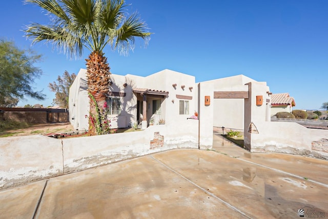 southwest-style home featuring stucco siding and fence