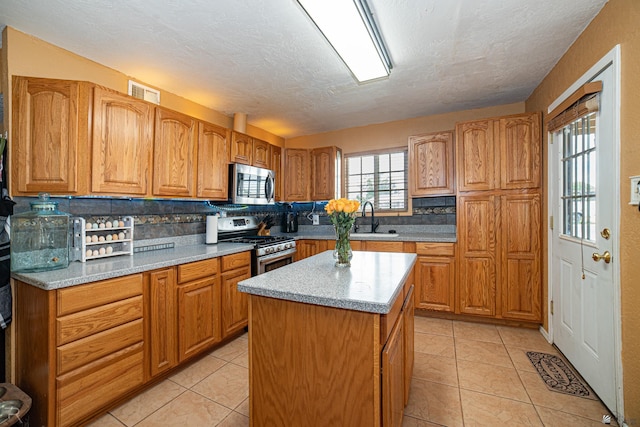 2556 W 14th St, Yuma, AZ 85364 - kitchen with stainless steel appliances, a sink, a kitchen island, a textured ceiling, and light tile patterned floors
