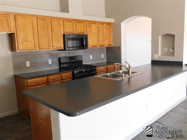 11785 E 27th Pl, Yuma, AZ 85367 - kitchen with gas range oven, a sink, arched walkways, dark countertops, and backsplash