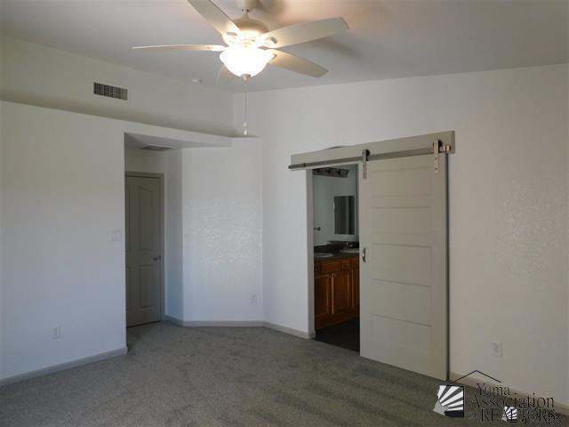 11785 E 27th Pl, Yuma, AZ 85367 - spare room featuring a barn door, carpet, ceiling fan, and baseboards