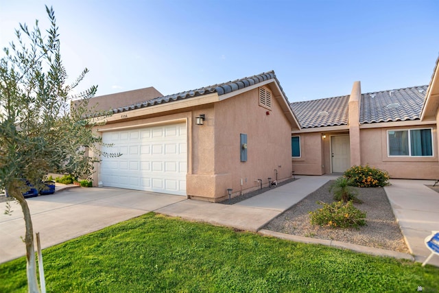 multi unit property with an attached garage, stucco siding, driveway, and a tile roof