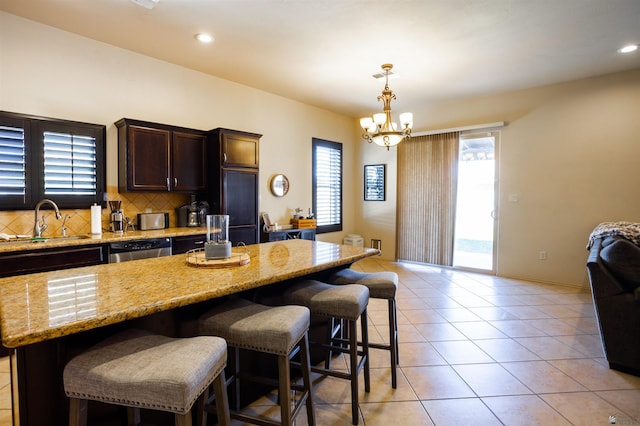 7942 E 36th Ln, Yuma, AZ 85365 - kitchen featuring a sink, stainless steel dishwasher, dark brown cabinets, a breakfast bar area, and decorative backsplash