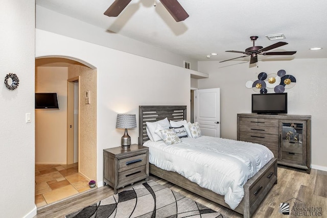 bedroom featuring light wood-style floors, arched walkways, recessed lighting, and visible vents