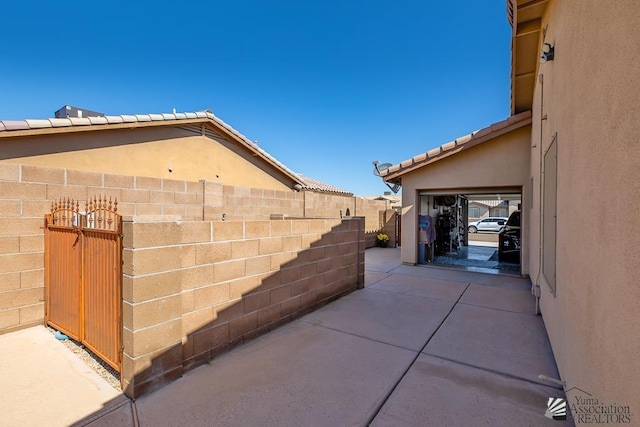 view of side of property featuring fence, a patio, and stucco siding