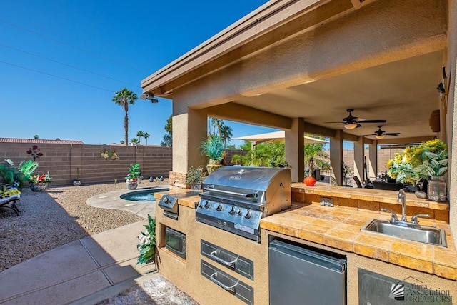 view of patio featuring a ceiling fan, an outdoor kitchen, a fenced backyard, a sink, and a grill
