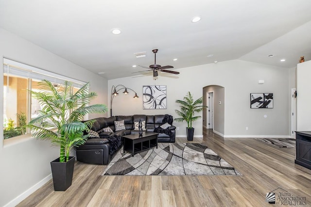 living area featuring arched walkways, baseboards, a ceiling fan, and wood finished floors