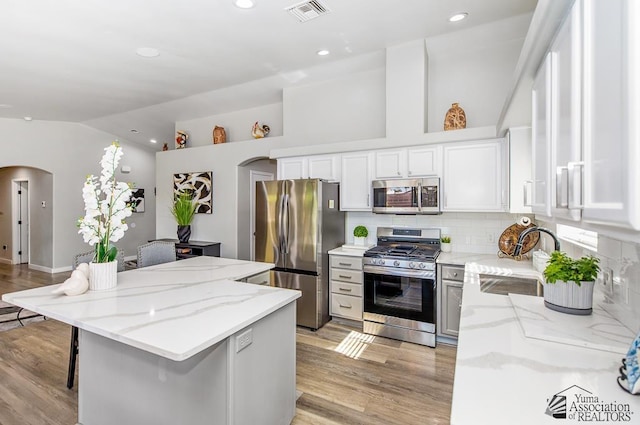 kitchen with a sink, arched walkways, stainless steel appliances, and visible vents